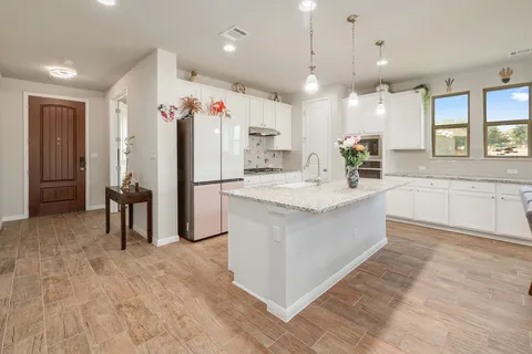 a large white kitchen with a refrigerator a oven and a sink