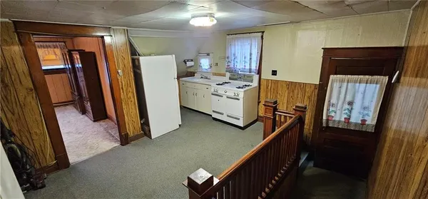 a view of a refrigerator in kitchen and an empty room