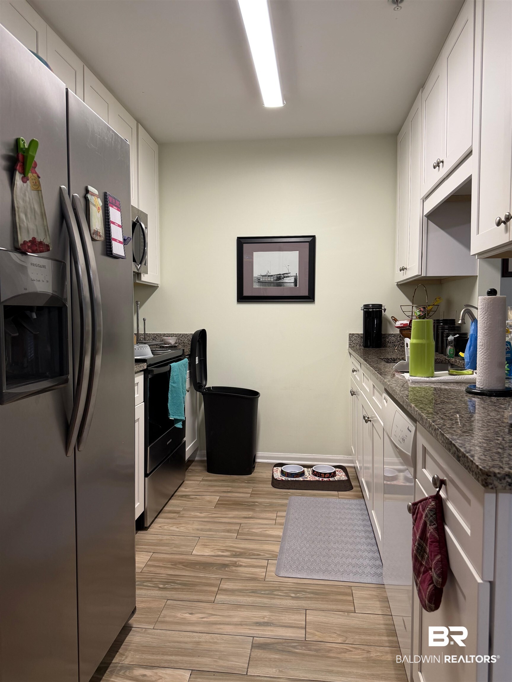 1517 Regency Road, Unit 71 Gulf Shores, AL 36542 - Photo 21 of 26 Kitchen featuring stainless steel appliances, white cabinets, wood finish floors, and dark stone counters