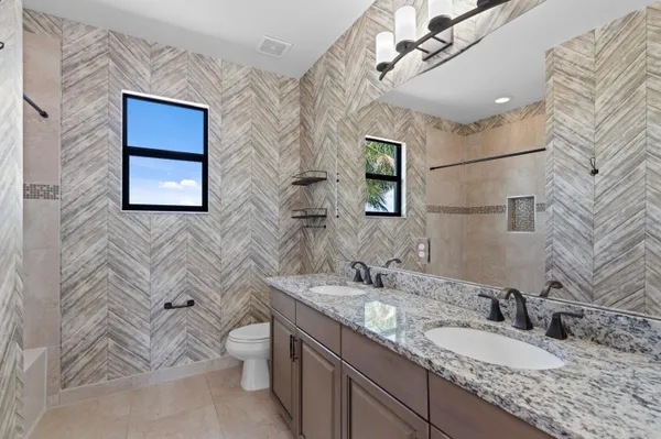 a bathroom with a granite countertop toilet a sink and mirror