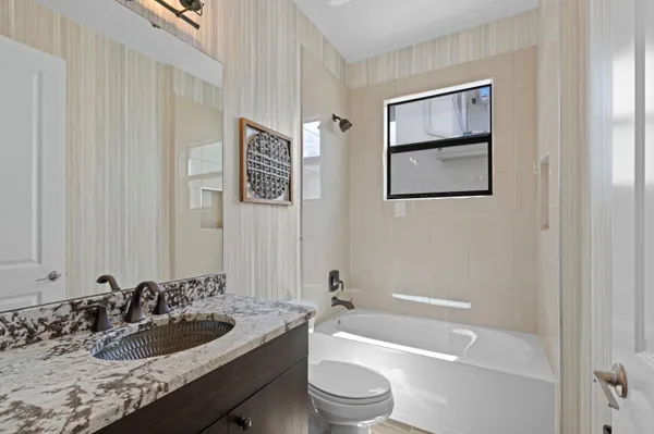 a bathroom with a granite countertop sink a toilet and bathtub