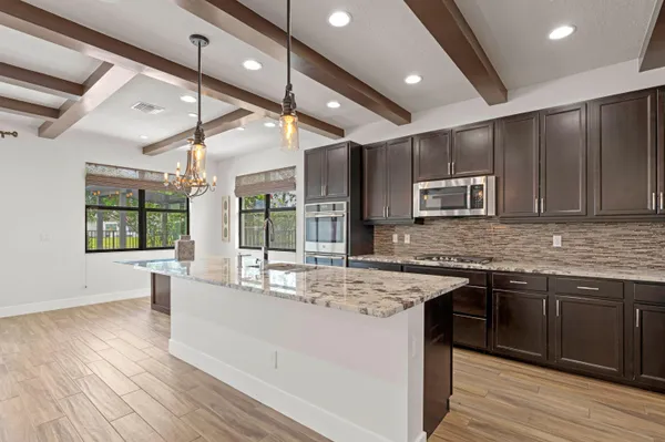 a large kitchen with stainless steel appliances granite countertop a lot of counter space and wooden floors