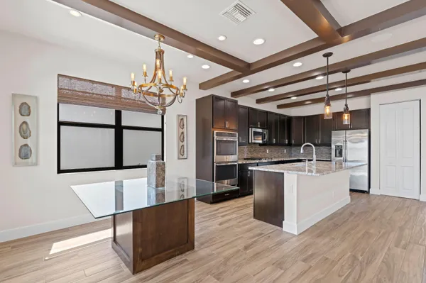 a kitchen with stainless steel appliances kitchen island granite countertop a table chairs and a refrigerator