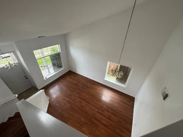 a view of an empty room with window and wooden floor