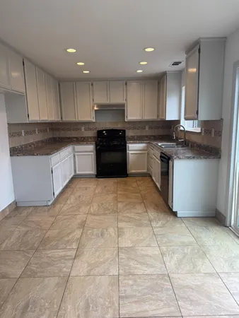a large kitchen with a stove a sink a microwave and cabinets