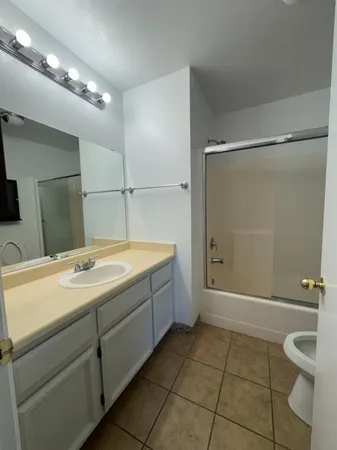 a bathroom with a granite countertop sink mirror and toilet