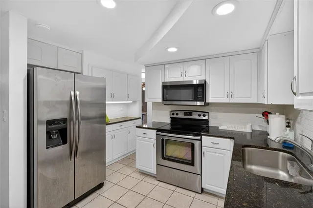 a kitchen with white cabinets stainless steel appliances and a sink