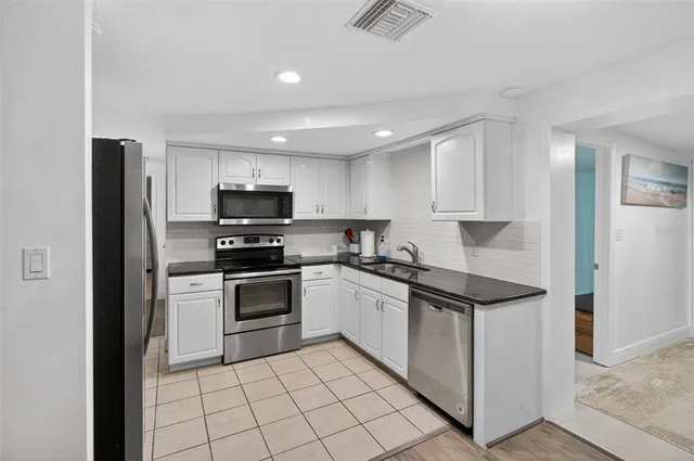 a kitchen with granite countertop a sink and white stainless steel appliances