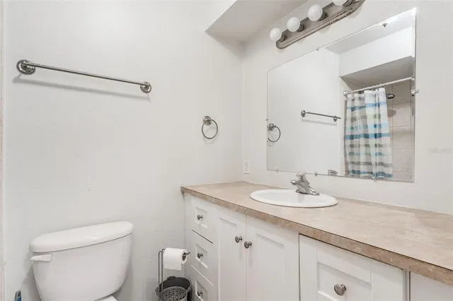 a bathroom with a granite countertop sink a toilet and shower