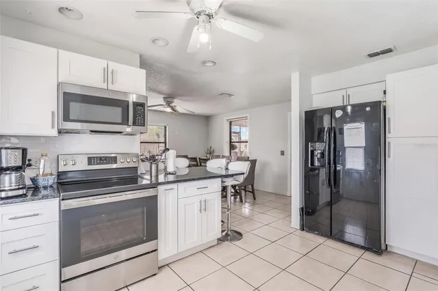 a kitchen with granite countertop a refrigerator stove top oven and sink