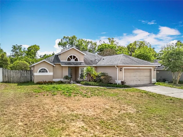 a view of a house with a big yard and large tree
