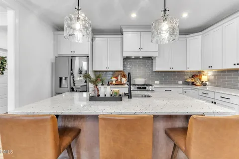 a kitchen with stainless steel appliances granite countertop a sink dishwasher a stove refrigerator and white cabinets with wooden floor