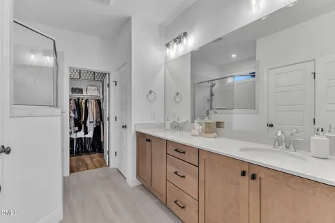 a bathroom with a double vanity sink a large mirror and shower