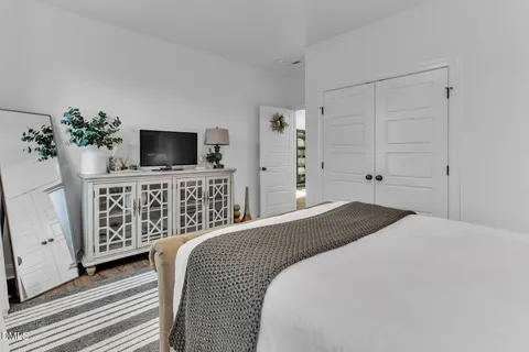 a bedroom with a bed and a flat tv screen on dresser