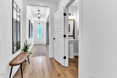 a view of a hallway with wooden floor and a bathroom