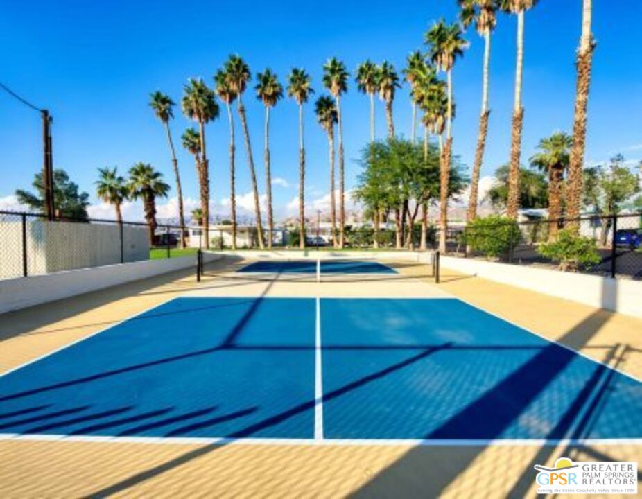 18131 Langlois Road, Unit H1 Desert Hot Springs, CA 92241 - Photo 41 of 44 a view of a swimming pool with a lawn chairs under palm trees