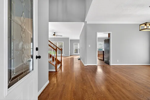 an empty room with wooden floor fan and windows