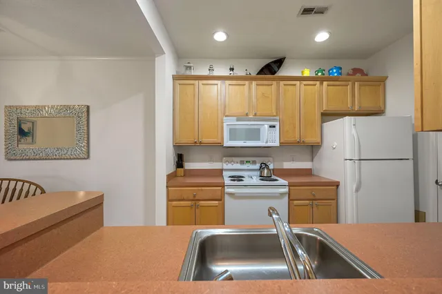 a kitchen with a refrigerator a stove a sink dishwasher and white cabinets with wooden floor