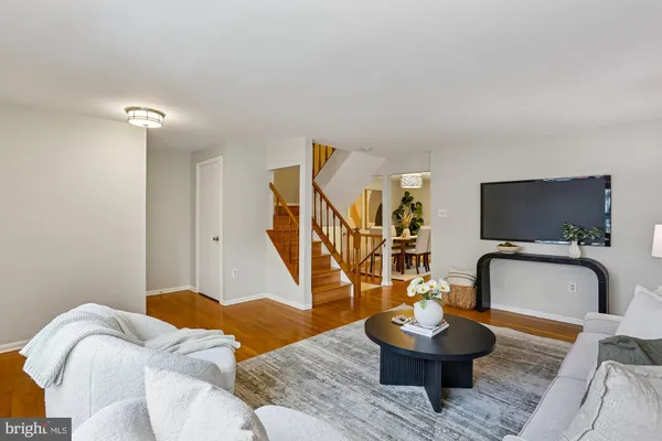 a living room with furniture and a potted plant on table with wooden floor