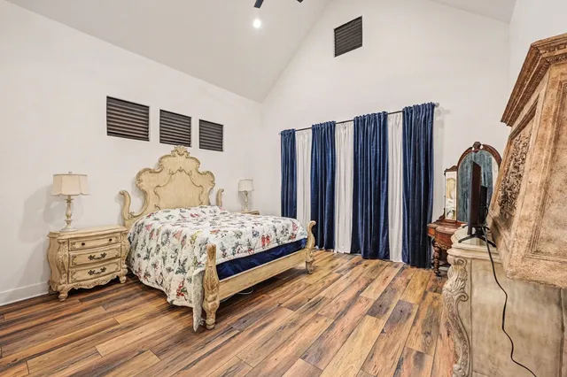 a bedroom with a bed wooden floor and a flat tv screen