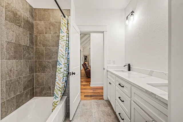 a bathroom with a double vanity sink a mirror and a bathtub
