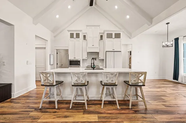 a kitchen with stainless steel appliances kitchen island granite countertop a dining table chairs and white cabinets