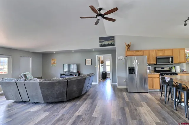 a living room with stainless steel appliances kitchen island a flat screen tv and a refrigerator