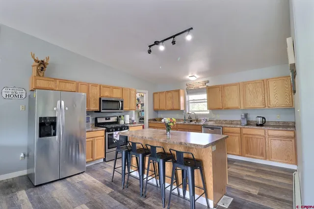 a kitchen with granite countertop a refrigerator a sink a stove a dining table and chairs