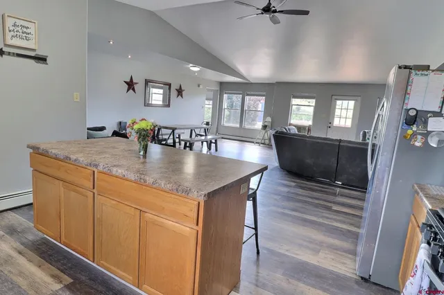 a dining hall with stainless steel appliances granite countertop a sink dishwasher and a dining table with wooden floor