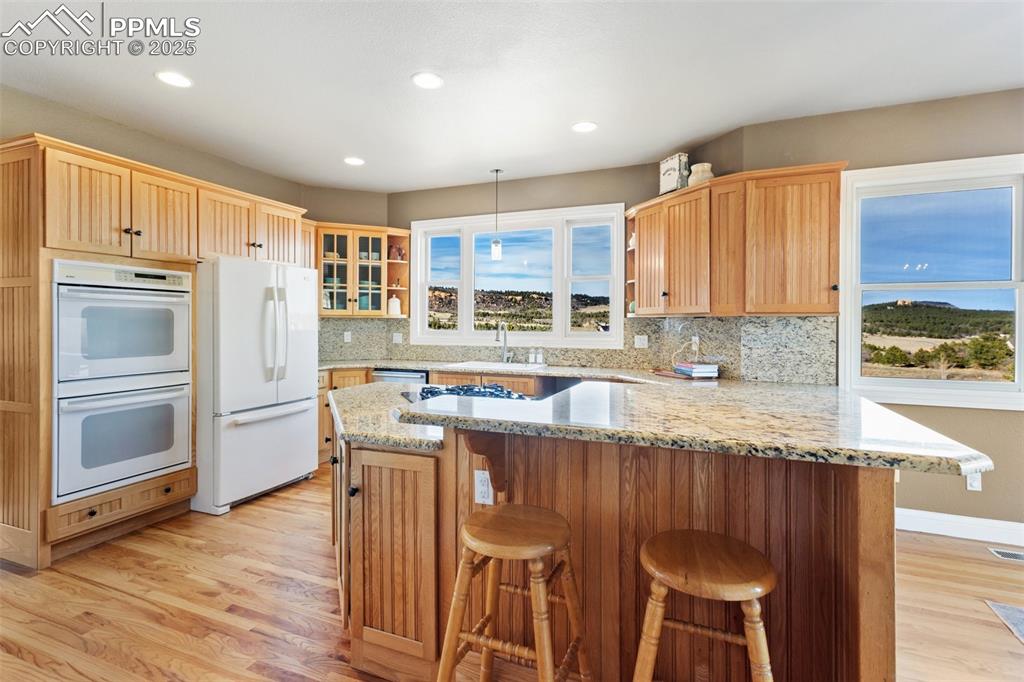 931 Forest View Road Monument, CO 80132 - Photo 13 of 50 a kitchen with stainless steel appliances granite countertop a refrigerator a stove a sink and white cabinets with wooden floor