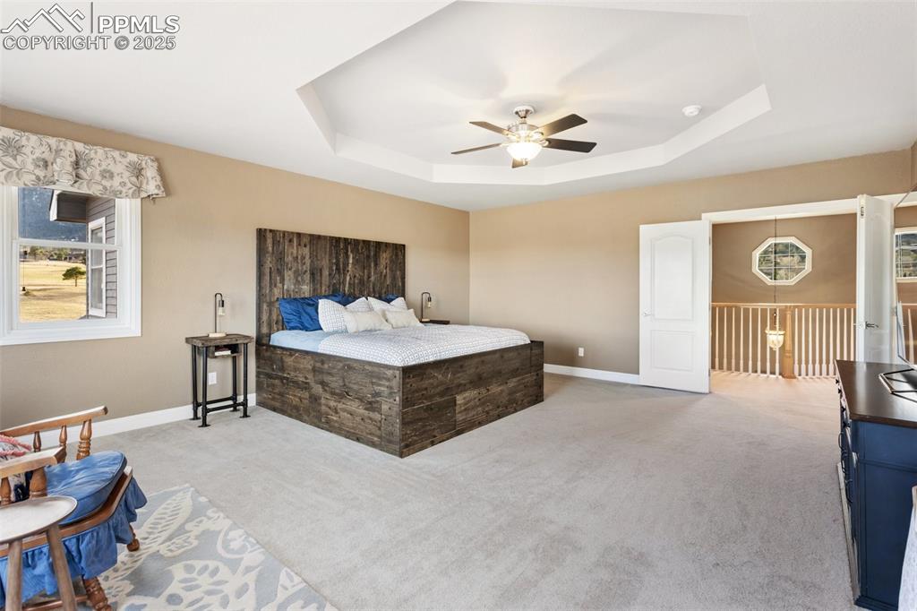 931 Forest View Road Monument, CO 80132 - Photo 24 of 50 a spacious bedroom with a bed and a chandelier