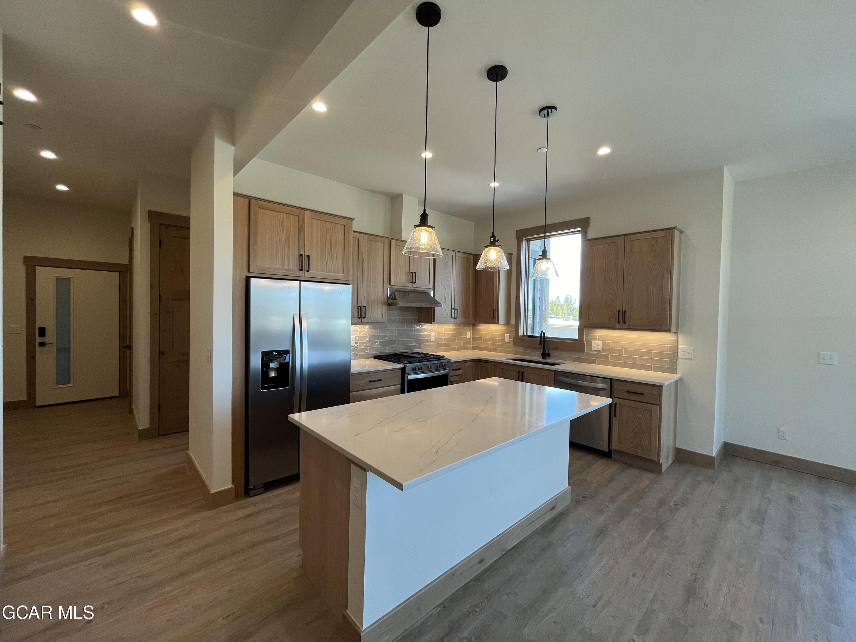 a large kitchen with a center island wooden floor stainless steel appliances and a window