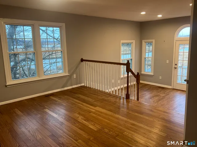 an empty room with wooden floor and windows