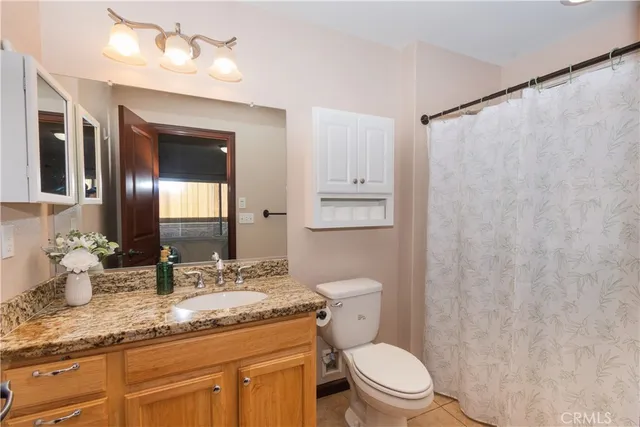 a bathroom with a granite countertop sink a mirror and a toilet