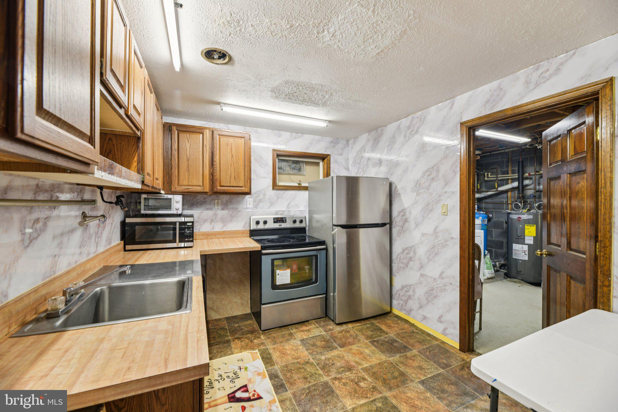 2650 Solomons Island Road Huntingtown, MD 20639 - Photo 33 of 44 a kitchen with stainless steel appliances granite countertop a refrigerator a stove and a sink with wooden floor
