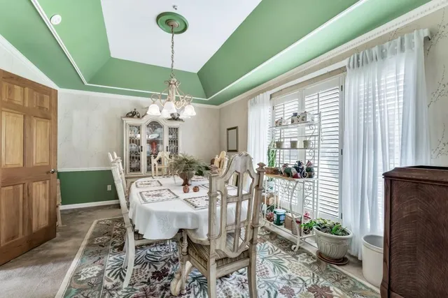 a dining room with furniture a potted plant and a large window