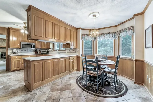 a kitchen with kitchen island granite countertop a stove a sink a refrigerator dining table and chairs