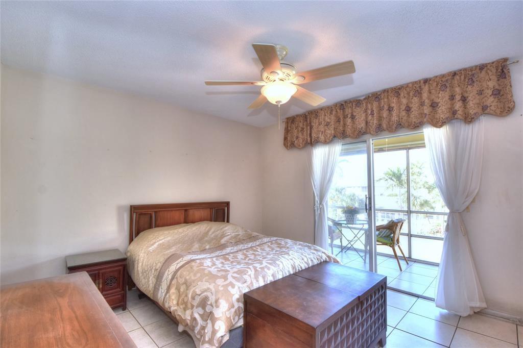 1951 Northeast 39th Street, Unit 360 Lighthouse Point, FL 33064 - Photo 14 of 28 a bedroom with a bed a chandelier and a large window