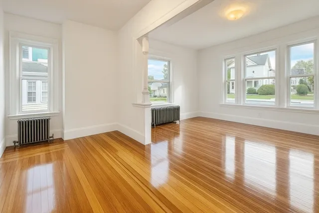 an empty room with wooden floor and windows