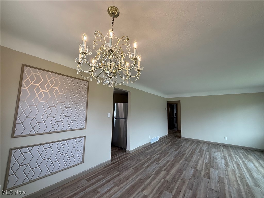 9417 Alexander Road Garfield Heights, OH 44125 - Photo 14 of 38 Empty room featuring visible vents, baseboards, an inviting chandelier, and dark wood-style floors