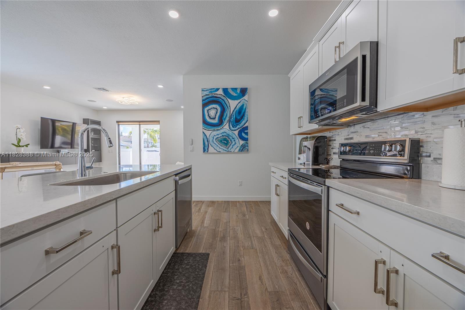 7126 Rockwood Road Jupiter, FL 33458 - Photo 6 of 30 a kitchen with stainless steel appliances granite countertop a stove a sink dishwasher and a microwave oven with white cabinets