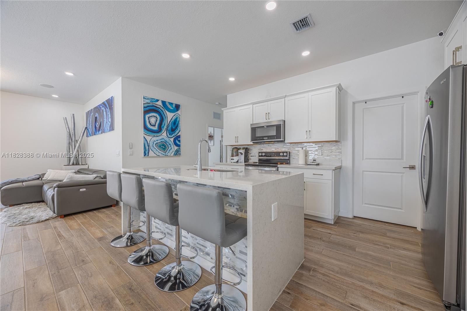 7126 Rockwood Road Jupiter, FL 33458 - Photo 7 of 30 a kitchen with stainless steel appliances kitchen island granite countertop a refrigerator a stove a sink a dining table and chairs with wooden floor