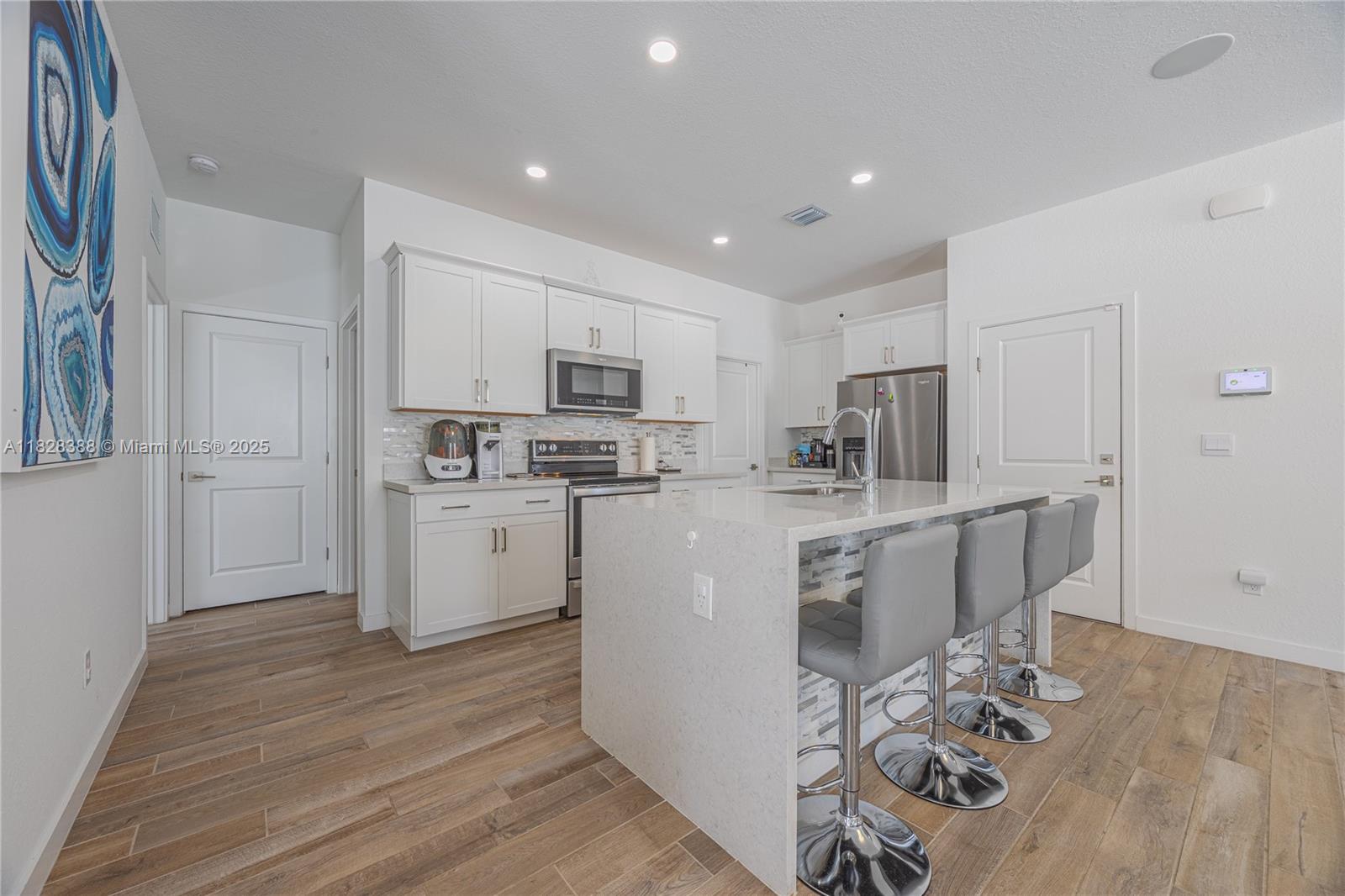 7126 Rockwood Road Jupiter, FL 33458 - Photo 8 of 30 a kitchen with white cabinets and stainless steel appliances