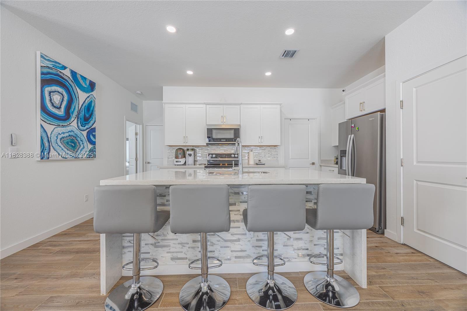 7126 Rockwood Road Jupiter, FL 33458 - Photo 9 of 30 a kitchen with a dining table chairs refrigerator and cabinets