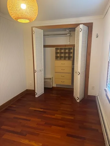 an empty room with wooden floor and cabinet