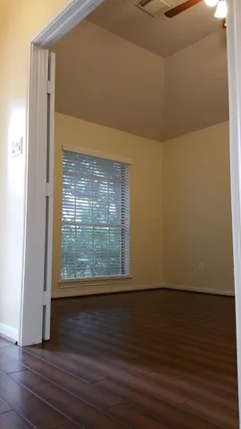 a view of an empty room with wooden floor and a window