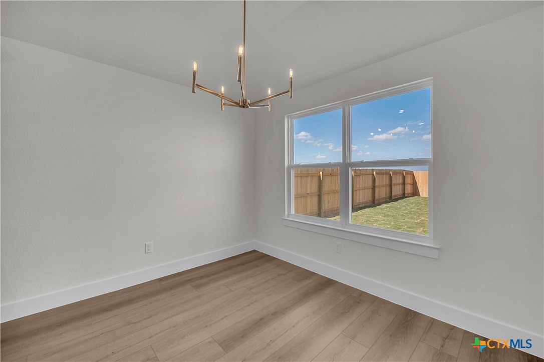 8913 Ponderosa Pine Road Temple, TX 76502 - Photo 7 of 16 an empty room with wooden floor a ceiling fan and windows