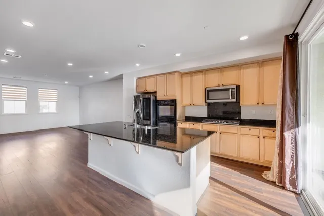 a large kitchen with stainless steel appliances a large counter top a stove a sink and a refrigerator