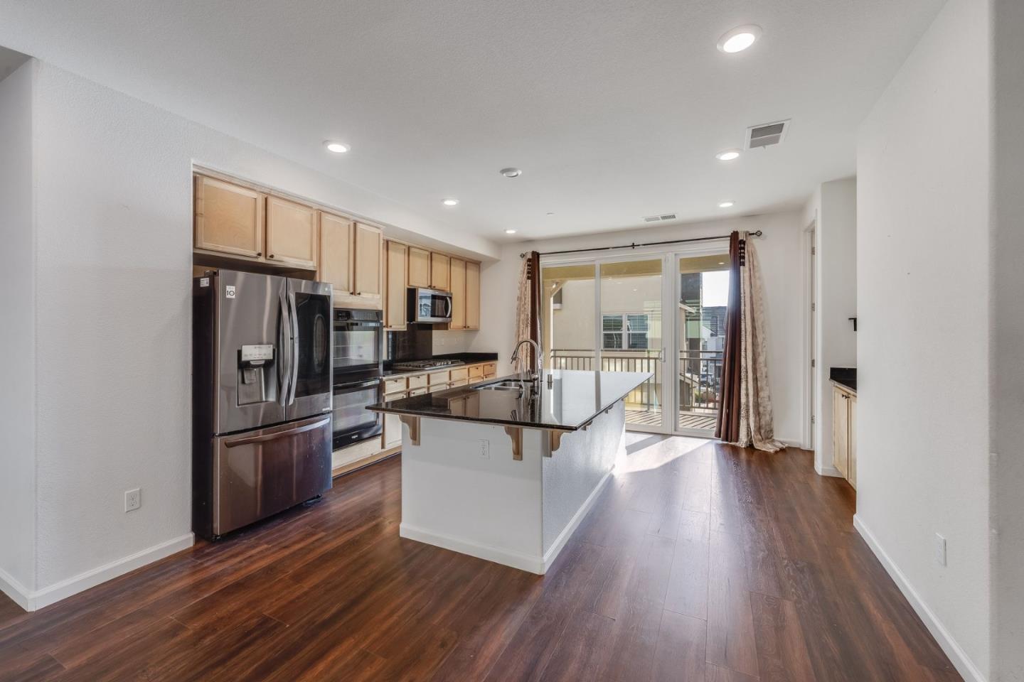 6914 Geyserville Street Dublin, CA 94568 - Photo 8 of 43 a kitchen with stainless steel appliances a refrigerator a sink dishwasher a stove and white cabinets with wooden floor