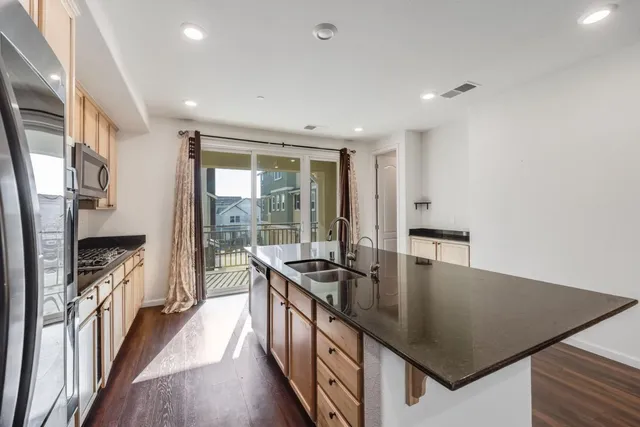 a kitchen with stainless steel appliances granite countertop a stove and a view of dining room